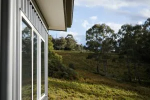 West side window of a Metal house with a view of a green field