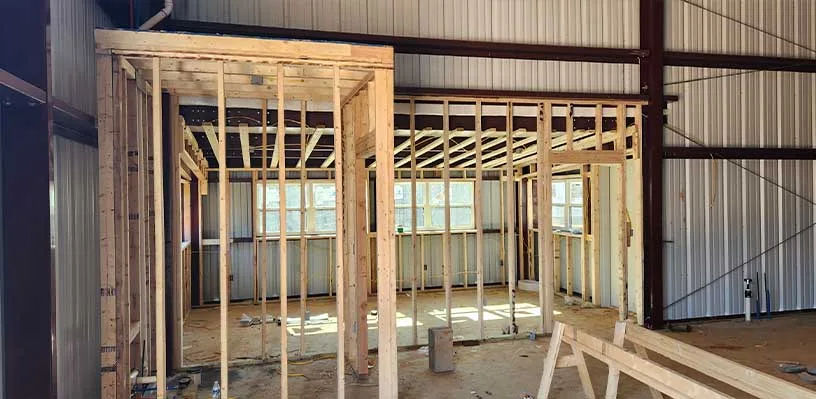 Unfinished interior construction with wooden framing and exposed beams, windows visible.